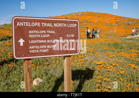 Lancaster, California - March 24, 2019: Sign in the Antelope Valley Poppy Reserve noting trail locations and distances. Tourists hiking in background Stock Photo