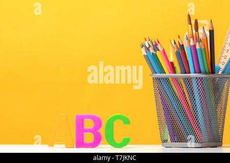 Set of stationery. Pencils, brushes, paints, letters of the alphabet A, B, C on the background of the yellow wall. The concept of education. Back to s Stock Photo