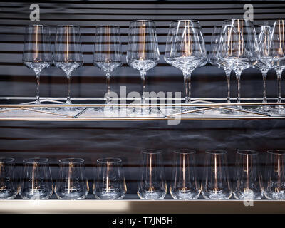 Brandy glasses and wineglasses standing on the shelf. Stock Photo
