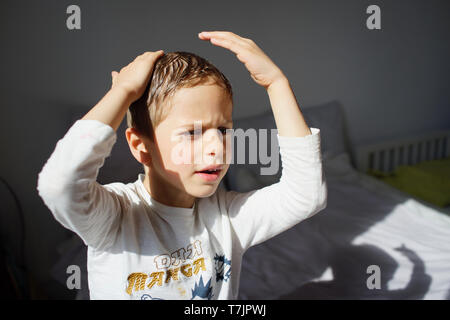 Young male child styling hair in mirror - boy of 5, 6 years old Stock Photo