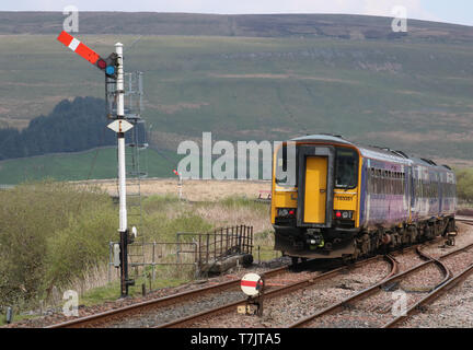 Northern train leaving at Garsdale station on the Settle to Carlisle railway line passing semaphore signal on 30th April 2019. Stock Photo