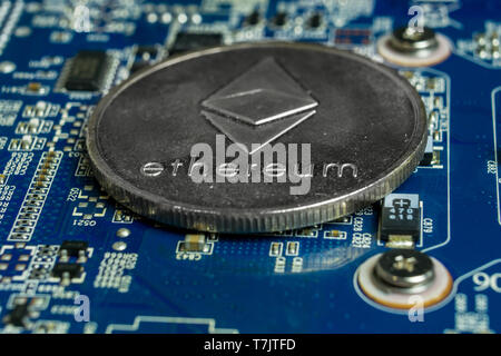 A single Ethereum coin on the blue computer motherboard Stock Photo