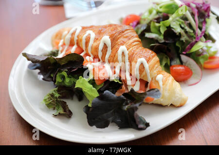 Croissant bread with salmon and salad on wooden background Stock Photo