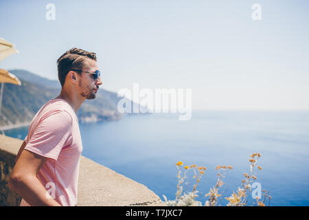 Back view of young man background stunning village. Tourist looking at scenic view of Manarola, Cinque Terre, Liguria, Italy Stock Photo