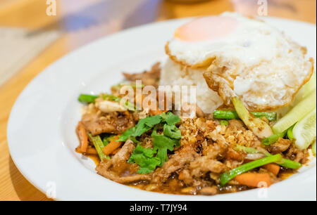 delicious Thai food garlic and pepper with pork and Fried egg with jasmin rice closeup with carrot cucumber Spring onion and coriander leaves on top i Stock Photo