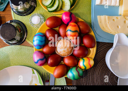 A top view on colored eggs arranged on a plate as a traditional symbol of Easter celebration in Germany together with other toppings. Stock Photo