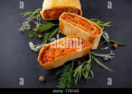 strudel with meat and mushrooms on a black board Stock Photo