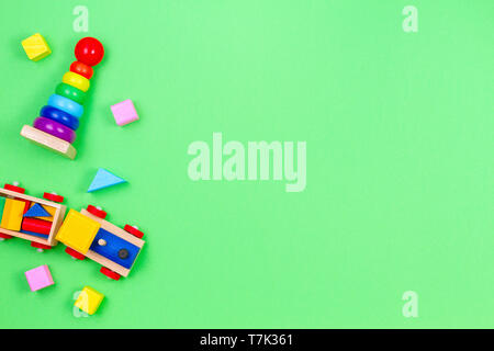 Wooden toy train, baby stacking rings pyramid and colorful blocks on green background Stock Photo