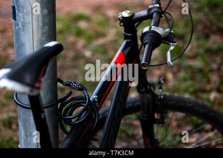 Black bicycle locked on to pole Stock Photo