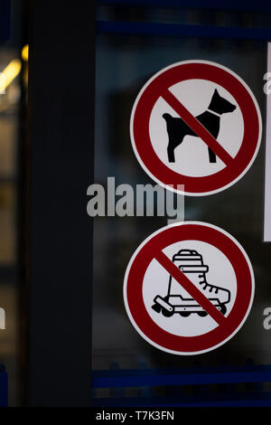 No dogs allowed, and no roller skates allowed, signs on glass door. Forbidden to do inside the mall. Stock Photo