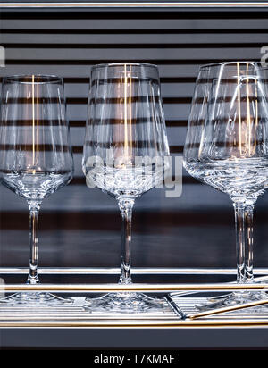 Brandy glasses and wineglasses standing on the shelf. Stock Photo