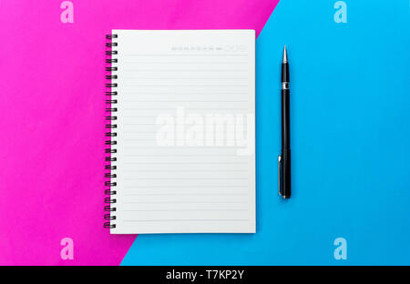 Top view blank notebook and black pen for mockup flat lay on blue and pink background. Stock Photo