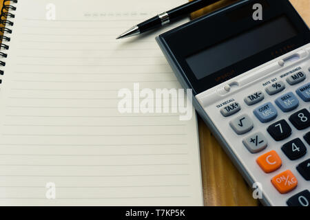 Business planning, finance and various taxes concepts. Blank notebook, black pen and calculator on wooden table with copy space. Depicts a the prepara Stock Photo