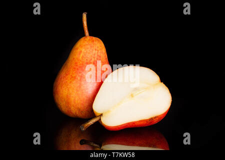 Group of one whole one half of juicy fresh red pear isolated on black glass Stock Photo