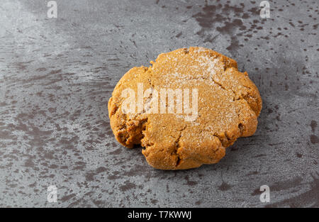 Side view of one molasses homemade cookie on a gray mottled background illuminated with natural lighting. Stock Photo