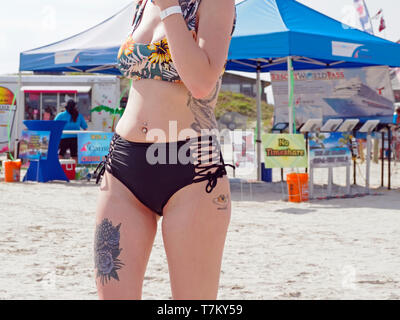 The tattooed body of a bikini clad woman at the 2019 Texas Sandfest in Port Aransas Texas USA. View from knee to shoulder Stock Photo