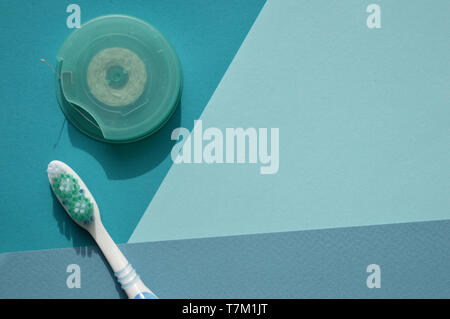 A toothbrush and dental floss on blue background of different tones. Combination of white, blue and turquoise. Stock Photo