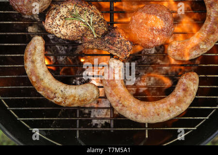Delicious cooked sausages with patties and steak on barbecue grill Stock Photo