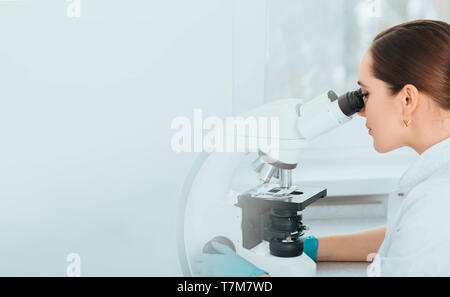 Scientist Looking Through Microscope and concentrate. Biological research Stock Photo