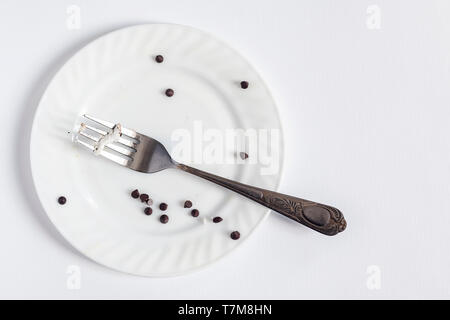 Empty dirty white plate and fork on the white background. Dirty plate with pieces and crumbs dessert. Copy space for text. Stock Photo