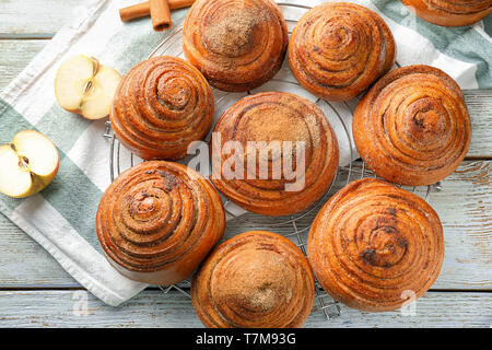 Cooling rack with sweet cinnamon buns on table Stock Photo