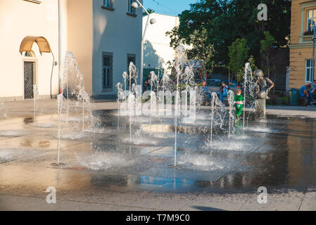 kids playing at city square near fountain. summer time Stock Photo