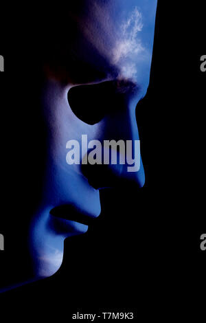 Robot face mask side view close up with textured skin and blank eyes. Black background and space for text. Artificial intelligence concept in a human  Stock Photo