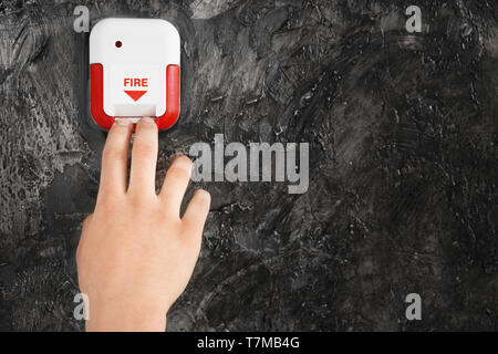 Young man using fire alarm system indoors Stock Photo