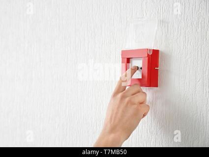 Young man using fire alarm system indoors Stock Photo