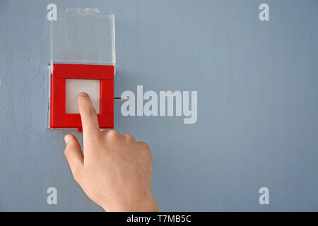 Young man using fire alarm system indoors Stock Photo