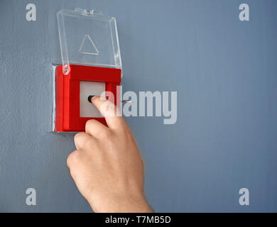 Young man using fire alarm system indoors Stock Photo