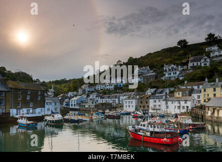 The little fishing boats fill the unspoilt pretty harbour as the sun drops lower over Polperro in south Cornwall. Stock Photo