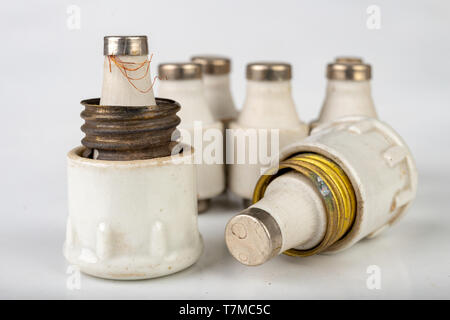 Old ceramic electric fuse. Blown and badly repaired security for energy, Bright background. Stock Photo