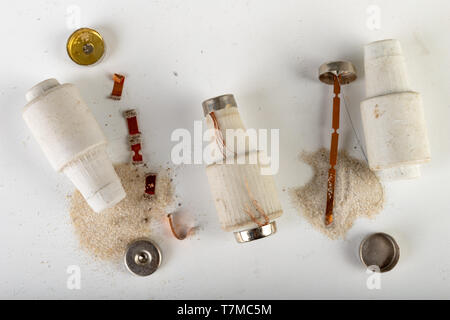Old ceramic electric fuse. Blown and badly repaired security for energy, Bright background. Stock Photo