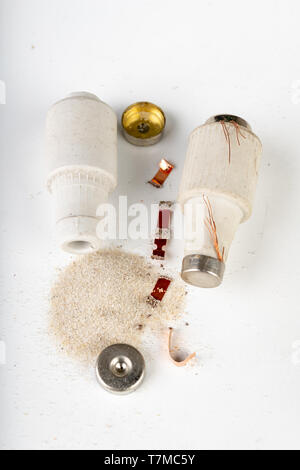 Old ceramic electric fuse. Blown and badly repaired security for energy, Bright background. Stock Photo