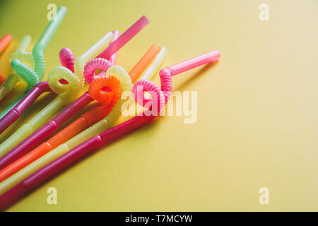 Colorful plastic drinking straws against yellow color background. Stock Photo