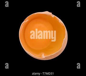 Broken hen egg with bright yolk inside close up. Top view isolated on black, clipping path included Stock Photo