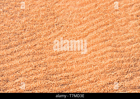 Shallow water at sandy sea coast with sun light into water close up. Texture and background Stock Photo