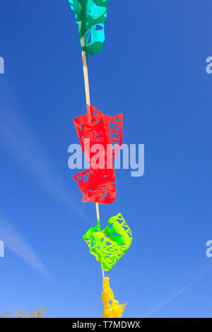 Multi-colored bunting wafting in the breeze below a blue sky in Tucson, AZ Stock Photo