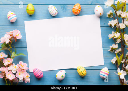 Colorful easter eggs background with white blank paper on wooden table Stock Photo