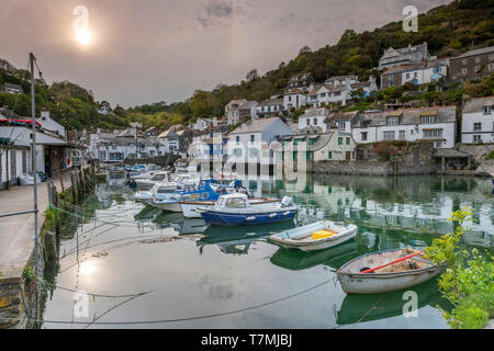 The little fishing boats fill the unspoilt pretty harbour as the sun drops lower over Polperro in south Cornwall. Stock Photo