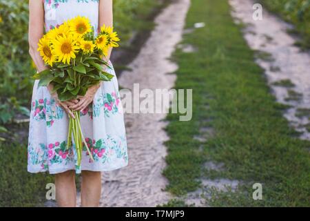 girl holding a huge bouquet of sunflowers in their hands Stock Photo