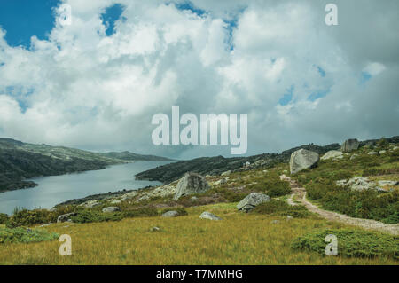 Hiking trail going through rocks and the Long Lake on highlands of Serra da Estrela. The highest mountain range in continental Portugal. Stock Photo