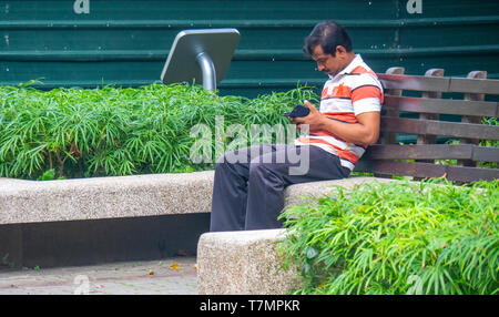 Man sitting on a bench using his mobile telephone. Stock Photo