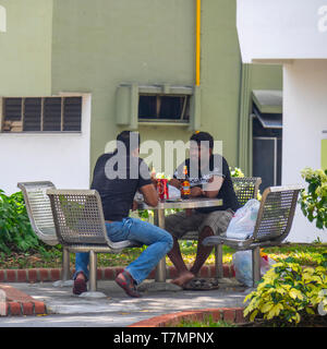 Two men sitting in a garden talking and drinking beer. Stock Photo