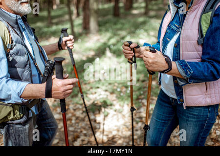 Senior man and woman hiking with trekking sticks in the forest, close-up view with cropped face Stock Photo