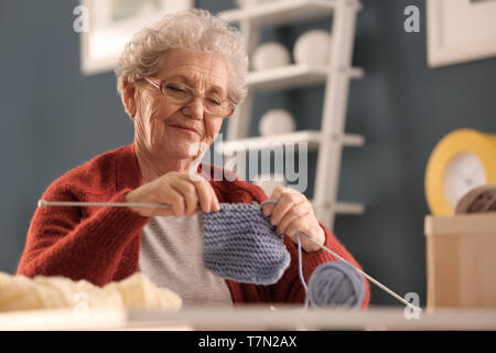 Senior woman knitting warm sock at home Stock Photo