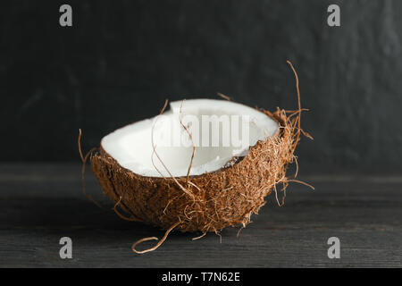 Half tropical coconut on wooden table against black background, space for text Stock Photo