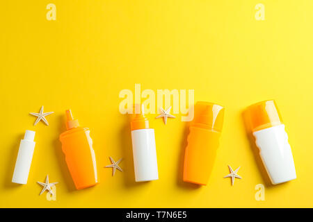 Flat lay composition with sunscreen sprays and starfishes on color background, space for text. Summer vacation backdrop Stock Photo