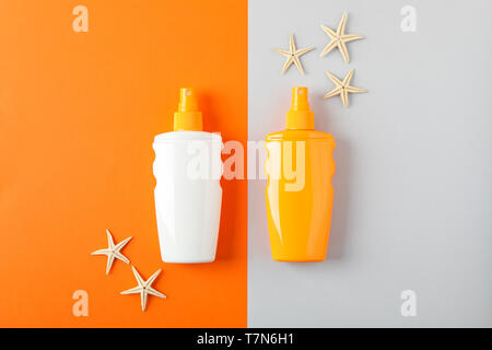 Flat lay composition with sunscreen sprays and starfishes on two tone background, space for text. Summer vacation backdrop Stock Photo